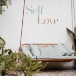landscape image of a couch against a wall, with the words self love written on the wall behind