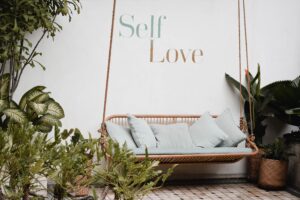 landscape image of a couch against a wall, with the words self love written on the wall behind