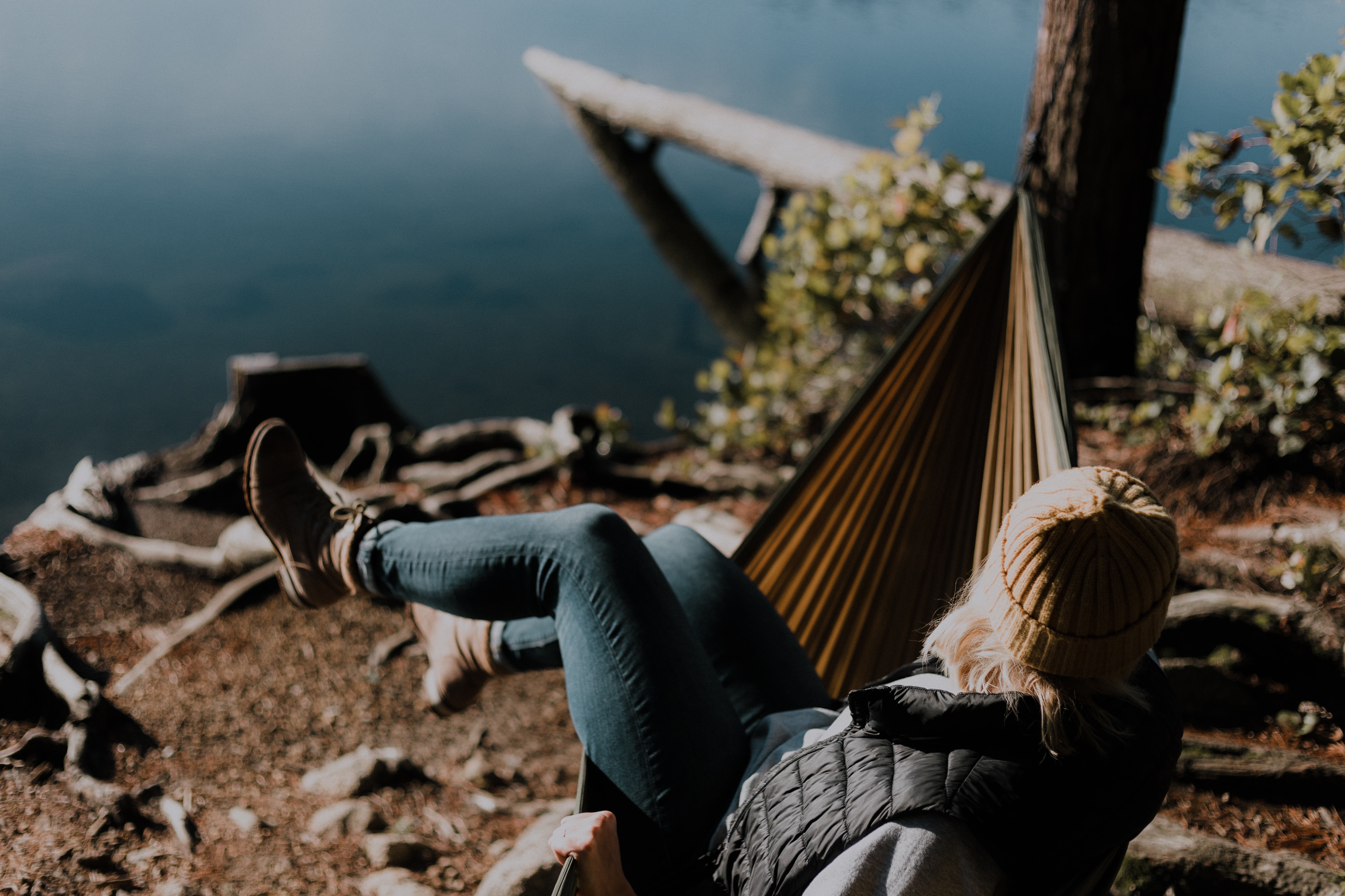image of woman relaxing alone in a hammock by a lake